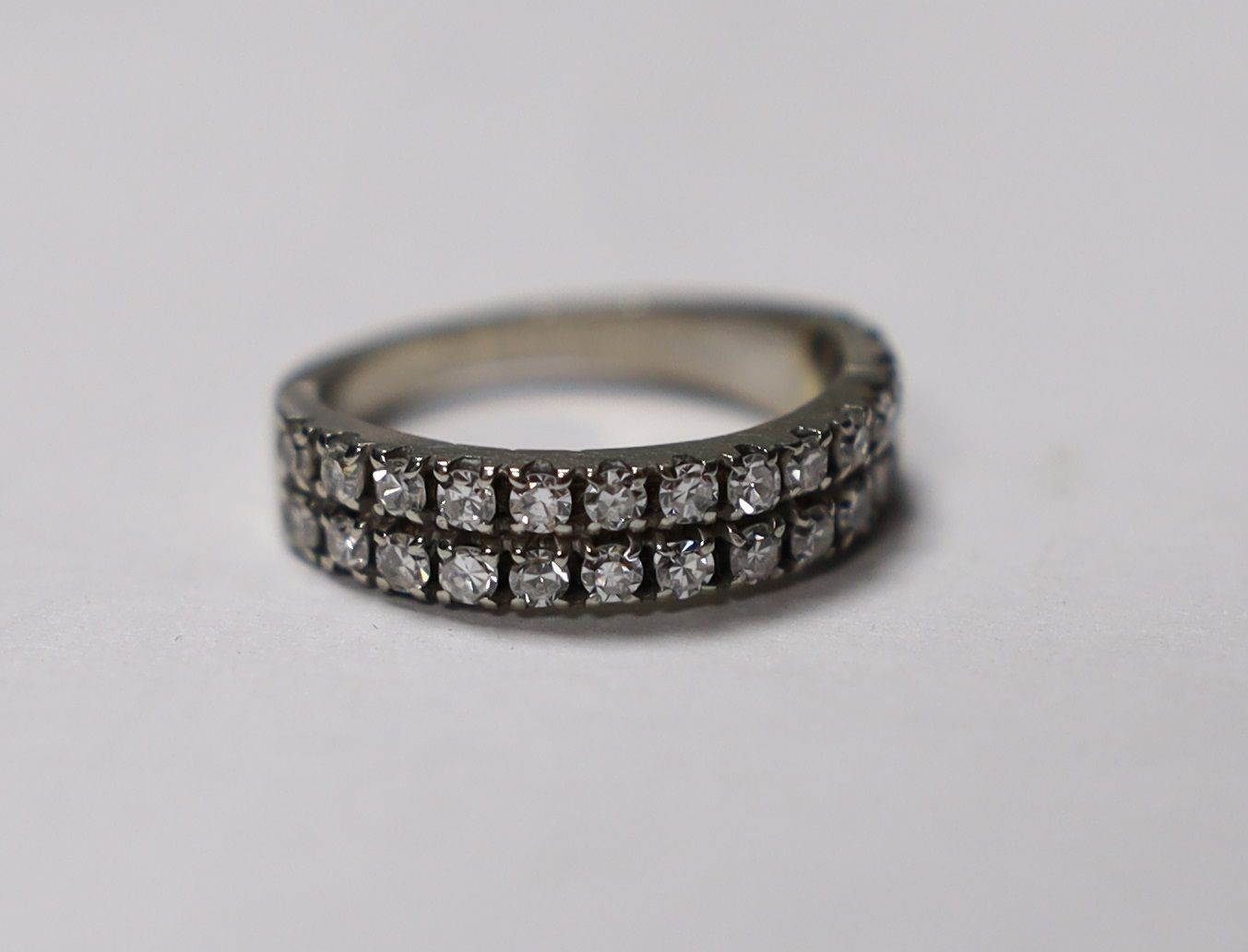 A white metal and two row round cut diamond set half eternity ring, size M, gross weight 3.9 grams.